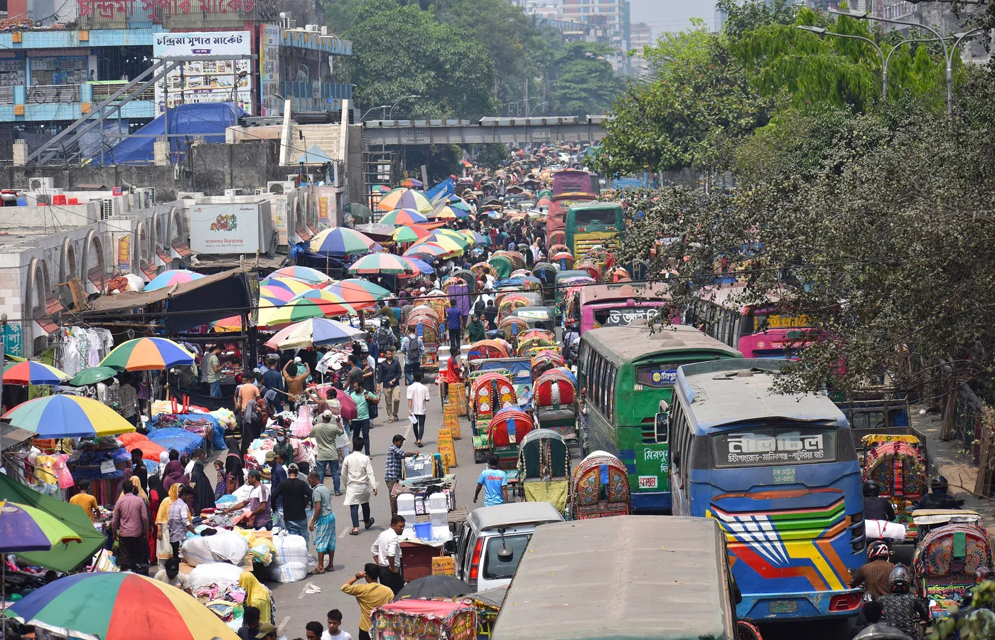 Rickshaws and market umbrellas filling a Dhaka street