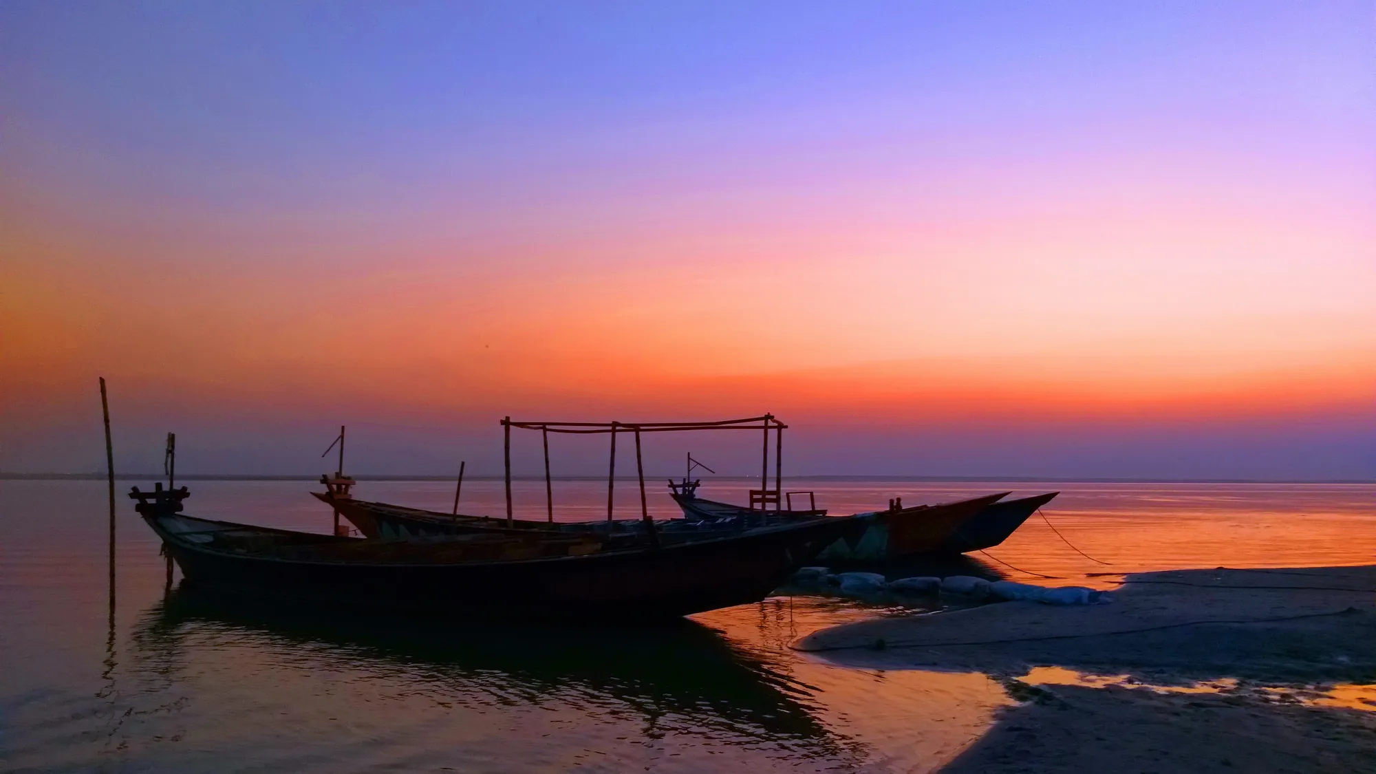 Boats silhouetted on a river at sunset